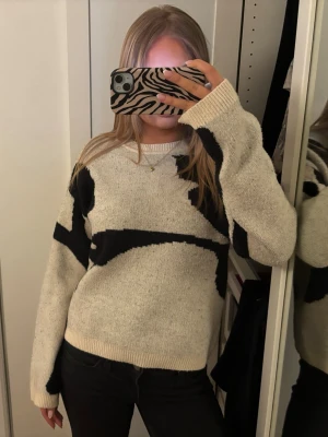 Beige/vit stickad tröja med svart mönster - En stickad tröja i beige/vit med abstrakt svart mönster. Tröjan har rund halsringning och långa ärmar med ribbade muddar. 💝💝