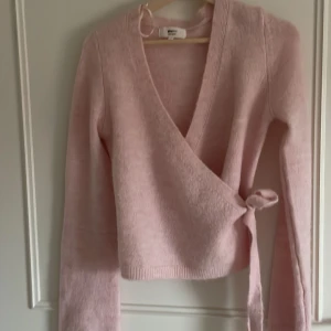 Ljusrosa omlottstickad tröja - Säljer denna jätte fina stickade tröjan från gina! Den är knappt använd och i jätte fint skick💕