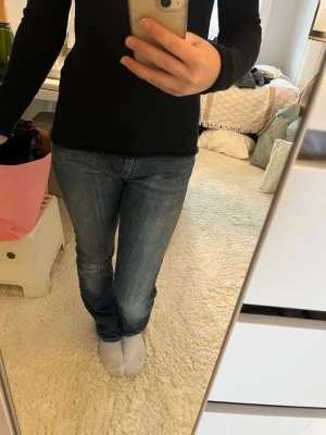 Blå low waist jeans - Säljer ett par blå low waist jeans. Jeansen har en snygg tvättad look och silverfärgade knappar och nitar. Perfekta för dig som gillar en avslappnad men ändå stilren stil.