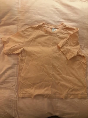 Ljusrosa t-shirt från Divided - Enkel och stilren ljusrosa t-shirt från Divided. Modellen har rund halsringning och korta ärmar. Tillverkad i mjuk bomull som känns skön mot huden. Perfekt basplagg för alla tillfällen och lätt att matcha med andra plagg.