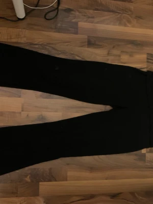 Svarta vida yoga pants - Säljer ett par svarta mjukisbyxor med hög midja och utsvängda ben. Byxorna har en enkel och clean look utan synliga loggor eller detaljer. Perfekta för en avslappnad stil och riktigt sköna att ha på sig. Materialet känns mjukt och stretchigt.