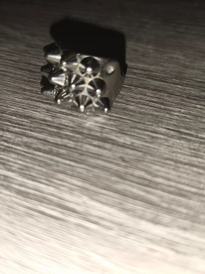 Silvrig ring med nitar och spikes - Cool ring i silverfärgad metall med flera nitar och spikes runt hela bandet. Ringen har en edgy och alternativ stil som sticker ut och passar perfekt för dig som gillar att uttrycka din personlighet med accessoarer.Den är lite smutsig så jag tvättar den innan jag skickar den ☺️