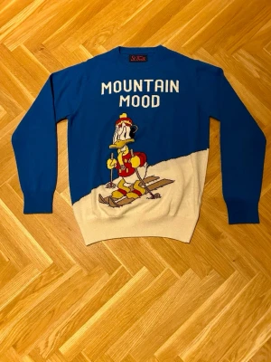 MC2 Saint Barth tröja - Sällsynt MC2 Saint Barth tröja med texten ”MOUNTAIN MOOD” och Kalle Anka på skidor. Stickad tröja i färgerna blå och vit. Storlek S