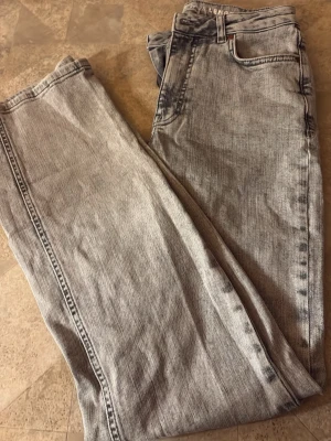 Grå bootcut jeans med mid waist - Säljer ett par grå tvättade jeans med bootcut passform och mid waist. Jeansen har klassisk femficksdesign och är tillverkade i denim. Perfekta för en avslappnad och trendig look.         Pris: 250 + frakt