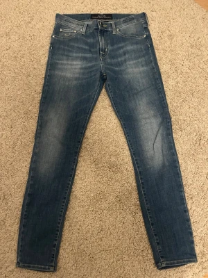 Jacob cohen jeans  - Säljer ett par blå  jeans från Jacob Cohen  med klassisk femficksdesign och snygga slitningar på låren. Jeansen har normal midja, smal passform och är tillverkade i stretchigt denimtyg för extra komfort. Perfekta till en avslappnad och trendig look. Det är modellen Kimbenly i storlek 28! 
