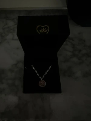 Halsband med smiley från Maria Nilsdotter - Super coolt halsband i silver från Maria Nilsdotter med en rund berlock som har ett smiley-ansikte. Kedjan är tunn och stilren, perfekt för att ge din outfit en lekfull touch. Levereras i original ask. Ny pris ca 2000 och den säljs inte längre!💓