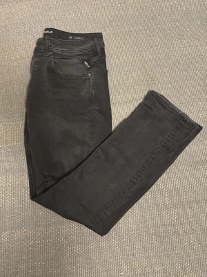 Svarta slim fit jeans från Replay - Ett par svarta jeans från Replay i modellen grover med snygga wash-stains i storlek 33/32. Jeansen är endast använda ett fåtal gånger. Säljer då jag växt ur jeansen, skriv om ni har några funderingar! Pris kan diskuteras.