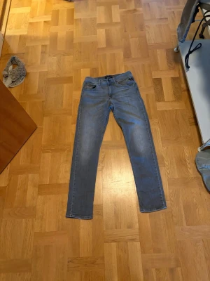 Gråblå slim fit jeans - Snygga gråblå slim fit jeans med klassisk femficksdesign och dragkedjegylf. Jeansen har en något tvättad look och raka ben. Perfekta för en avslappnad och trendig stil.