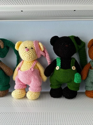 Handgjorda virkade nallar - Styckpris: 270kr  Dessa handgjorda virkade nallar är tillverkade av bomullsgarn. Varje nallebjörn bär ett par hängselbyxor och en matchande mössa. Knapparna på hängselbyxorna är märkta med "Handmade with love". Nallarna finns i olika färger. Pris kan diskuteras vid köp av fler.