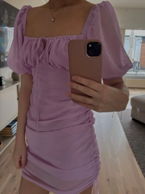 Ljuslila kort klänning med puffärm - Supersöt ljuslila kort klänning med puffärmar och fyrkantig urringning. Har aldrig använt denna superfina klänning då jag inte tycker om den på mig ! Super fin till fest eller till sommaren . Storlek 36 men skulle säga att den passar om man har storlek 34 också ! 