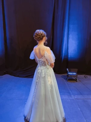 Ballklänning - Magisk ljusblå långklänning med tunna axelband och transparent överdel dekorerad med blommig spets. Kjolen är i flera lager tyll för en drömmig look och ärmarna är luftiga och avtagbara. Perfekt för bal eller student!