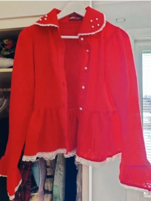 Röd spetskofta med pärlknappar Lolita egl Japanese fashion  - Riktigt söt röd kofta från Body Line med spetsdetaljer och pärlknappar. Koftan har volang nedtill och vita spetskanter på krage och ärmslut. 