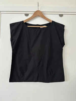 Svart topp med dragkedja bak, storlek 40 - Stilren svart ärmlös topp / linne / blus från ATT. i storlek 40. Snygg silverfärgad dragkedja baktill och tidlös rundad halsringning. V-formad söm framtill som ger en fin detalj. 100% bomull, så bra material som andas. Passar bra till både vardags och fest. Mycket gott skick, som ny!  (Skickas helst, men kan även hämtas i Stockholm vid behov)