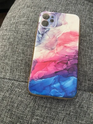 Färgstarkt mobilskal med abstrakt mönster - Snyggt mobilskal med abstrakt mönster i blått, rosa och lila toner. Skalet är gjort i plast och har transparenta kanter. Passar perfekt för dig som vill ha ett unikt och färgglatt skydd till din mobil. Passar till IPhone 11