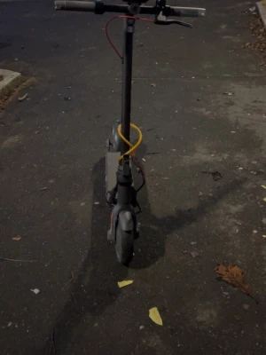 Svart Navee V50i PRO elscooter med LED-lampa - Säljer en svart elscooter med LED-lampa framtill och gula samt röda kablar. Scootern har breda handtag och robusta hjul, perfekt för att ta sig runt i stan. Laddningsuttag och bromshandtag syns tydligt på styret. Endast Göteborg 