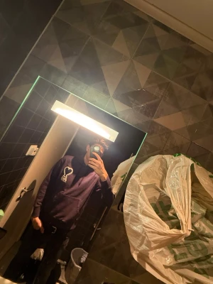 Lila Ami Paris hoodie med hjärtdetalj - Säljer en lila hoodie från Ami Paris med stor vit hjärtdetalj och bokstaven A på bröstet. Hoodien har huva med dragsko och en stor magficka. Perfekt för dig som gillar streetwear och vill ha något som sticker ut. Hör av er vid funderingar😊