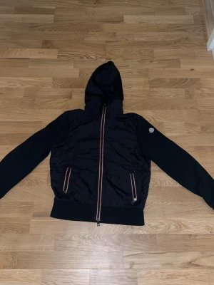 Svart vindjacka med huva från Moncler - Snygg svart vindjacka från Moncler med huva. Perfekt till våren. Använd få antal gånger. Hör av er vid frågor 