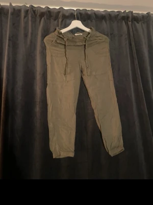 Olivgröna mjukisbyxor  - Säljer ett par olivgröna mjukisbyxor med resår i midjan och två sidofickor. Perfekta för chill dagar eller när du vill vara bekväm.