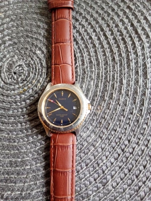 Casio klocka med brunt läderband herr/dam water resistant 100 M. - Stilren Casio klocka med mörkblå urtavla och klassiskt brunt läderband med krokodilpräglat mönster. Boetten är i silverfärg och har tydliga indexmarkeringar. Perfekt accessoar för dig som gillar tidlös design. Nr 1332 MTH 3008. Water Resistent 100 M. Fungerar men ev nytt batteri.