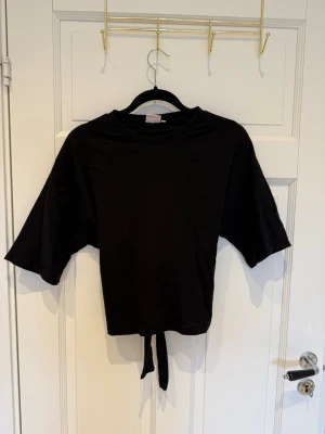 Populär knyt topp från Nelly  - Gullig kortärmad tröja från Nelly med knyte baktill, så söt nu till sommaren