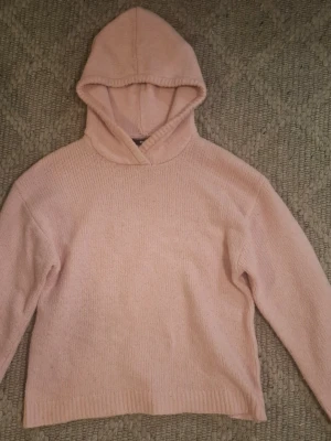 Ljusrosa stickat hoodie från BikBok - Mysig ljusrosa stickad hoodie från BikBok i stickat material. Tröjan har en stor huva och är tillverkad i mjukt tyg som passar perfekt för en avslappnad look. Enkel design utan tryck eller detaljer, med ribbade muddar vid nederkant och ärmslut. Pris kan diskuteras❤️