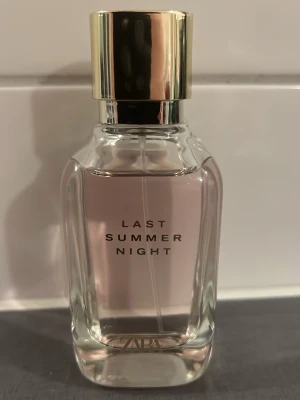 Zara Last Summer Night parfym - Zara Last Summer Night parfym i en elegant, genomskinlig glasflaska med ljusrosa doftvätska och guldfärgat lock. Flaskan har raka, mjuka kanter och stilren text på framsidan. Perfekt för dig som gillar fräscha och moderna dofter.