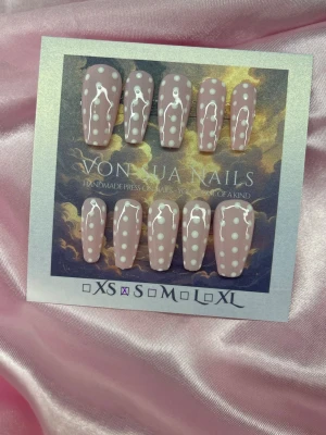 BabyDot (S);Medium Ballerina - Handgjorda press-on naglar i babypink med vita prickar. Naglarna har en medium lång, ballerina form design och är perfekta för dig som vill ha en unik och trendig look. I storlek S: 15 mm, 11,5 mm, 12 mm, 11 mm, 9 mm  och designen är noggrant målad för hand.