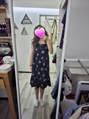 Svart blommig midiklänning - Säljer en svart klänning med smala axelband och blommigt mönster i vitt och blått. Klänningen har en lös passform och volang nedtill, vilket ger en avslappnad och luftig känsla. Perfekt för varma dagar och enkel att styla med accessoarer.