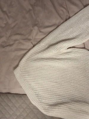Vit stickad tröja från Zara Knit - Säljer en krämvit stickad tröja från Zara Knit. Tröjan har en avslappnad passform, ribbstickad rund halsringning och är tillverkad i ett mjukt, grovt stickat material. Perfekt för lager på lager och enkel att styla till olika outfits.
