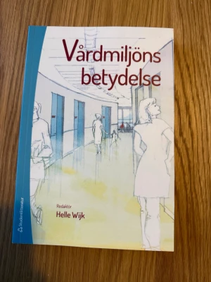 Vård­miljöns betydelse  - Kursbok med titeln 'Vård­miljöns betydelse', redaktör Helle Wijk. Boken har ett omslag i blå och vit ton med illustration av en vårdmiljö. Perfekt för dig som studerar vård, arkitektur eller miljöpsykologi.