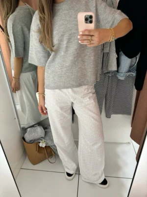 Ljusgrå stickad tröja - Snygg ljusgrå stickad tröja med oversized passform och korta ärmar. Tröjan har rund halsringning och är tillverkad i ett mjukt material som ger en avslappnad look. Perfekt att styla med både jeans och vida byxor.