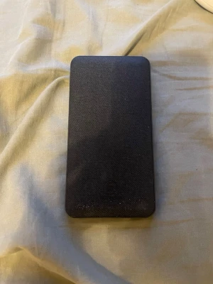 Svart powerbank från Hama - En stilren svart powerbank från Hama med slimmad, rektangulär design. Tillverkad i plast och har teknisk info tryckt på baksidan. Perfekt för att ladda mobilen eller andra enheter när du är på språng.