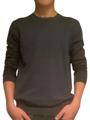 Mörkblå stickad tröja från Sisley - En stilren mörkblå stickad tröja från Sisley med rund halsringning och ribbade muddar vid ärmslut och nederkant. Perfekt för lager på lager och enkel att matcha med jeans eller chinos.