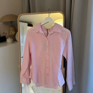 Rosa och vit randig skjorta Designbysi - Säljer en snygg rosa och vit randig skjorta från DESIGNBYSI. Lappen kvar och är helt oanvänd. Superfin till sommaren. 