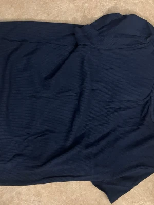 Mörkblå ribbad T-shirt  - En enkel och stilren mörkblå tshirt med ribbad struktur. Tröjan har korta ärmar och rak passform, perfekt för en avslappnad men ändå snygg look. Materialet känns mjukt och följsamt mot kroppen.