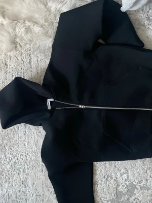 Weekday Scuba Zip Hoodie – Svart (S) - Säljer en nästan helt ny svart hoodie från Weekday med dragkedja framtill och stor huva. Hoodien har två stora fickor på magen och är gjord i mjukt bomullsmaterial. Perfekt för en chill och avslappnad stil.