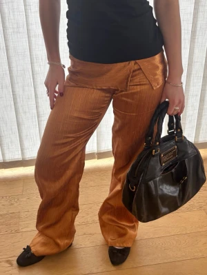 Kopparfärgade unika low waist vida fest byxor  - Säljer dessa fantastiska byxor, perfekta för fest!! 💕💕De är lågmidjade, sydda i ett kopparfärgat tyg. Obs ska ha snöre🩷De är sydda av mig och är därför helt unika! Likande dom från beshka. Passar ca s, jag är 162 cm. Har ett snöre i midjan där man kan spänna in, men de är inte stretchig så kan vara svåra att få på sig. Ställ gärna frågor och kika gärna på mina andra annonser! Kommer även ladda upp fler saker jag sytt till våren/sommaren, så följ gärna. 💗