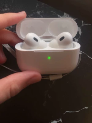 Trådlös aipods hörlurar  - Säljer ett par vita  AiPods Pro med trådlöst laddningsetui. Hörlurarna har en stilren och kompakt design med silikonproppar och laddas via USB-C. Perfekta för musik, samtal och träning tack vare brusreducering och smidig passform.