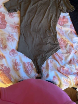 Olivgrön body från MISU - Säljer en enkel och stilren olivgrön body från MISU i storlek S. Bodyn har korta ärmar och rund halsringning. Materialet känns mjukt och stretchigt, perfekt för att matcha med jeans eller kjol. Klassisk modell utan synliga detaljer.