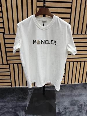 Märkeskläder  - Snygg vit t-shirt  med klassisk rund hals och svart logotyptryck på bröstet. Tillverkad i mjuk bomull som känns skön mot huden. Perfekt för dig som gillar stilrena och exklusiva plagg.