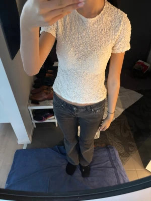 Vit ribbad topp med kort ärm - Säljer en söt vit topp med ribbad struktur och korta ärmar. Toppen är figurnära och har en lätt croppad passform som passar perfekt till jeans eller kjol. Enkel och stilren design utan synliga märken eller loggor. Har använts få gånger så som ny❣️