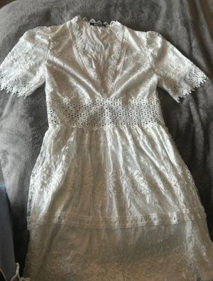 Vit spetsklänning  - Superfin vit klänning från Gina Tricot i spets med v-ringning och korta ärmar. Helt nytt skick och sitter superfint på! Perfekt till studenten🤍Skriv för frågor