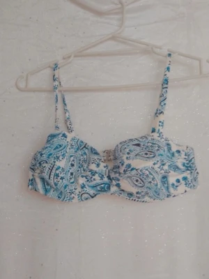Blåvit bikiniöver paysleymönster - Bikiniöverdel i blått sop vittrvit med paisleyinspirerat mönster. Smala axelband och lätt vadderade kupor för en bekväm och snygg look. pipeline soppar sommarkän underlying och for dig som vill sticka knut på stranden. Kupa 80B