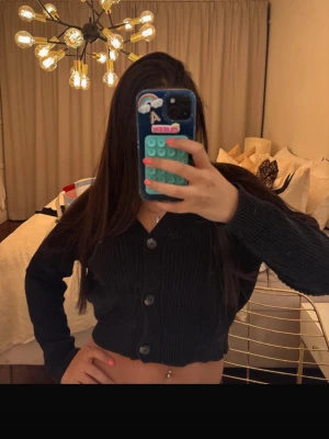 Svart cropped kofta - Säljer en svart cropped kofta med stora knappar framtill. Koftan är ribbstickad.