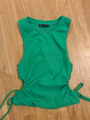 Grön ribbad linnetopp från Zara -  grön ribbad linnetopp från Zara med stripade snörningardsdetaljer i sidorna. Toppen är i storlek M