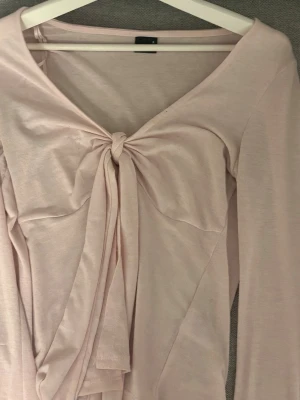 Ljusrosa topp med knyt från Gina Tricot - Supersöt ljusrosa topp från Gina Tricot med lång ärm och snygg knytning framtill. Storlek S