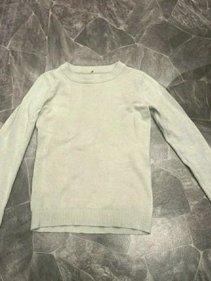 Beige stickad tröja  - En enkel och stilren ljusgrå stickad tröja med rund halsringning och ribbade muddar vid ärmslut och nederkant. Perfekt basplagg för lager på lager och passar till det mesta i garderoben.