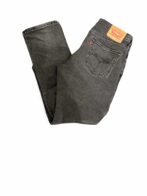 Grå jeans från Levi's - Snygga grå jeans från Levi's med klassisk femficksdesign och raka ben. Jeansen har en ikonisk läderpatch bak i midjan och tydliga sömmar. Perfekta för en avslappnad och trendig stil. 31/30