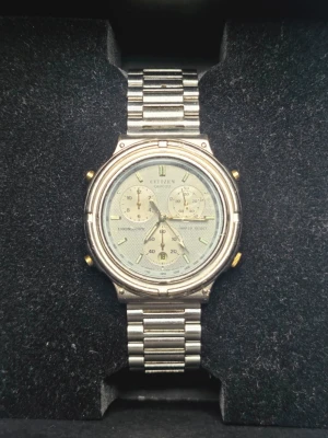 Citizen Quartz Herrklocka - Stilren kronografklocka från Citizen med silverfärgat armband i metall och rund urtavla. Urtavlan har flera små visare och detaljer i guld, samt tydliga indexmarkeringar. Klassisk design som passar till många olika stilar. Klockan går som den ska men hackar och beter sig konstigt i tidsinställningsläge
