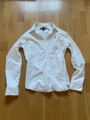 Ralph lauren skjorta - Vit Ralph lauren skjorta i storlek XS/S. Passar dig mellan 160-170. Den är i mycket bra skick och det är bara att höra av sig vid minsta fundering.